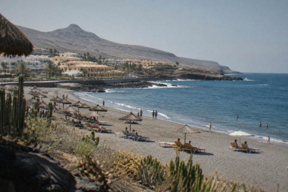 Wide sandy beach in a resort town with sunbeds and a calm sea