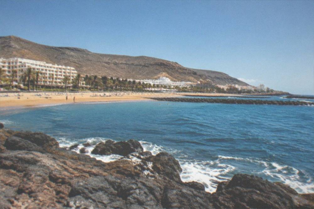 A calm swimming beach with breakwaters and sunbeds at Las Vistas in Arona