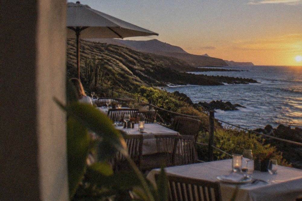 A seafront restaurant terrace in Tenerife at dusk with tables set for dinner