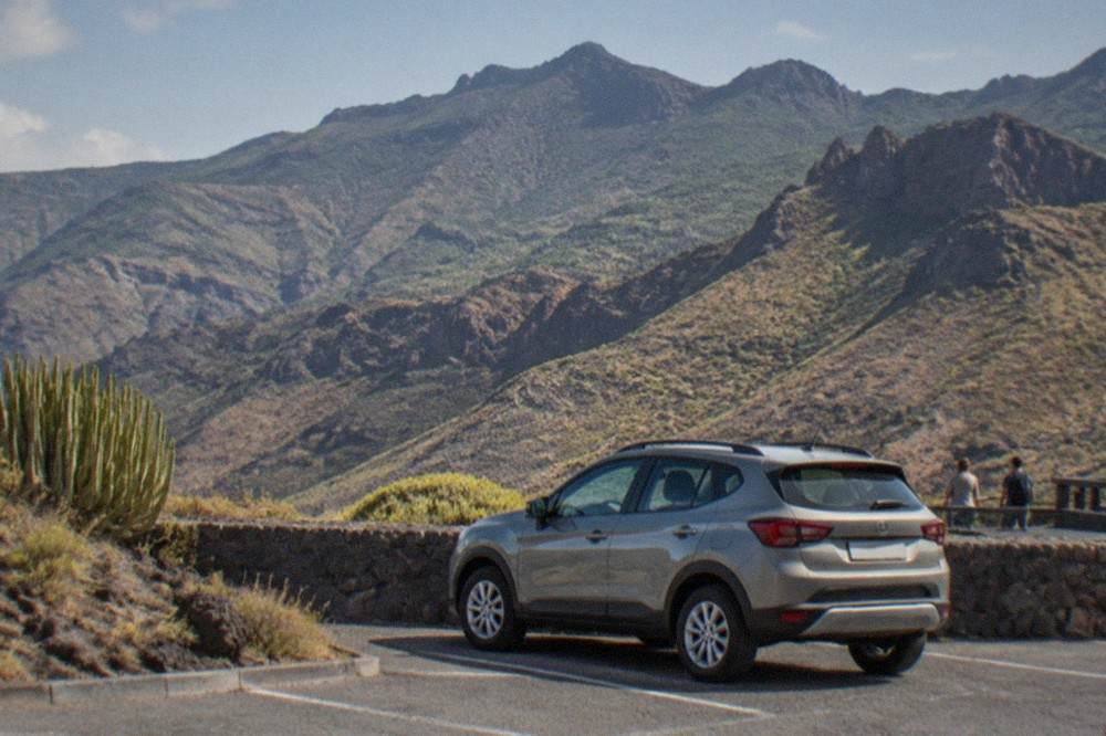 A parked hire car beside a viewpoint overlooking green mountains in Tenerife