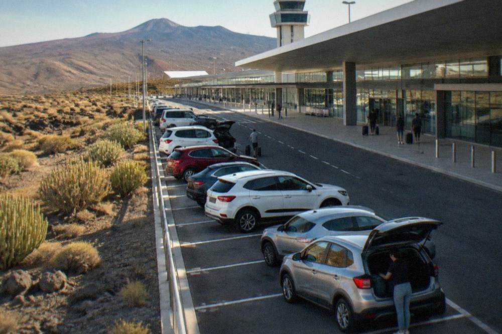 A row of hire cars parked outside an airport terminal in Tenerife