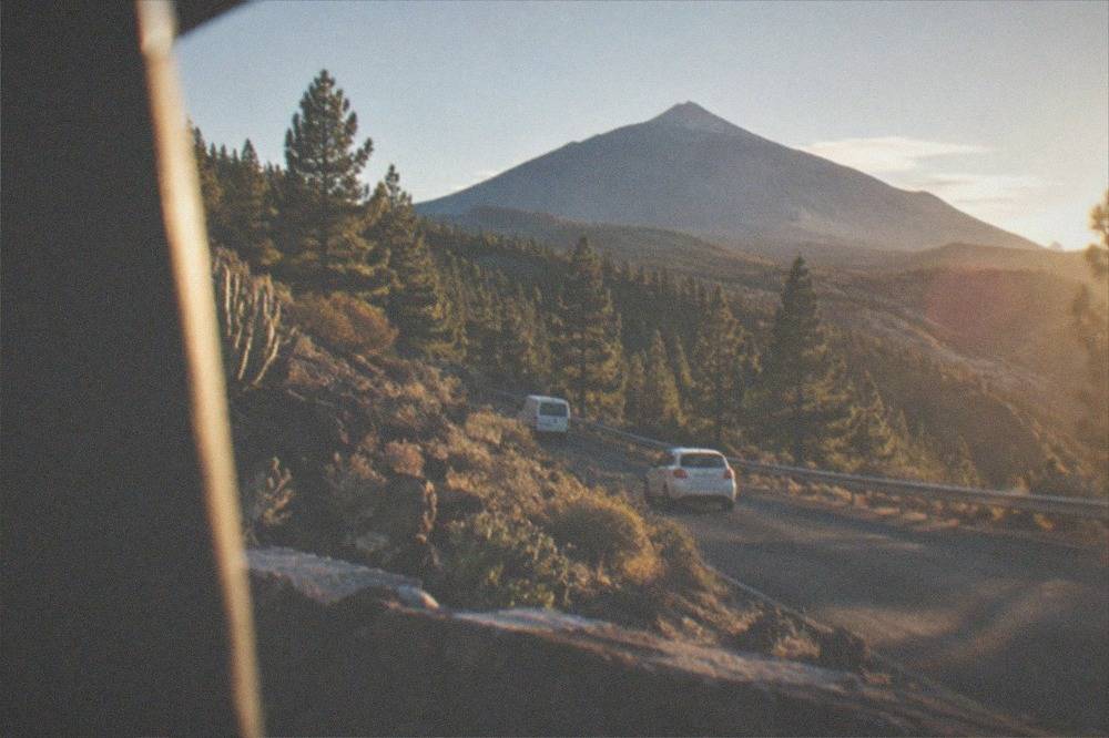 A winding mountain road climbing through pine forest toward Mount Teide
