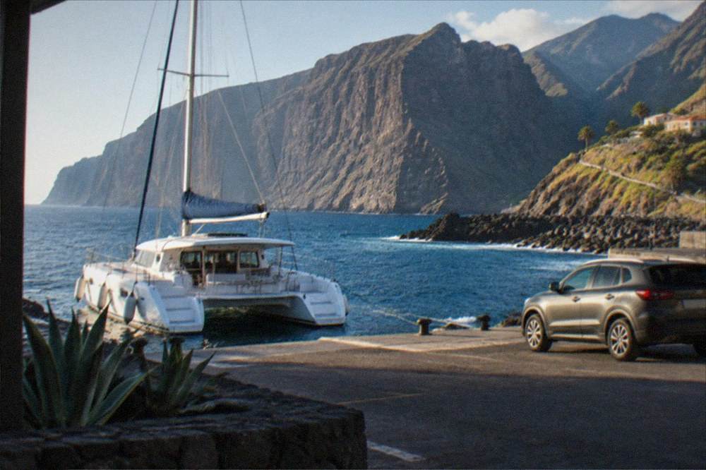 A catamaran and a hire car parked side by side at Los Gigantes harbour