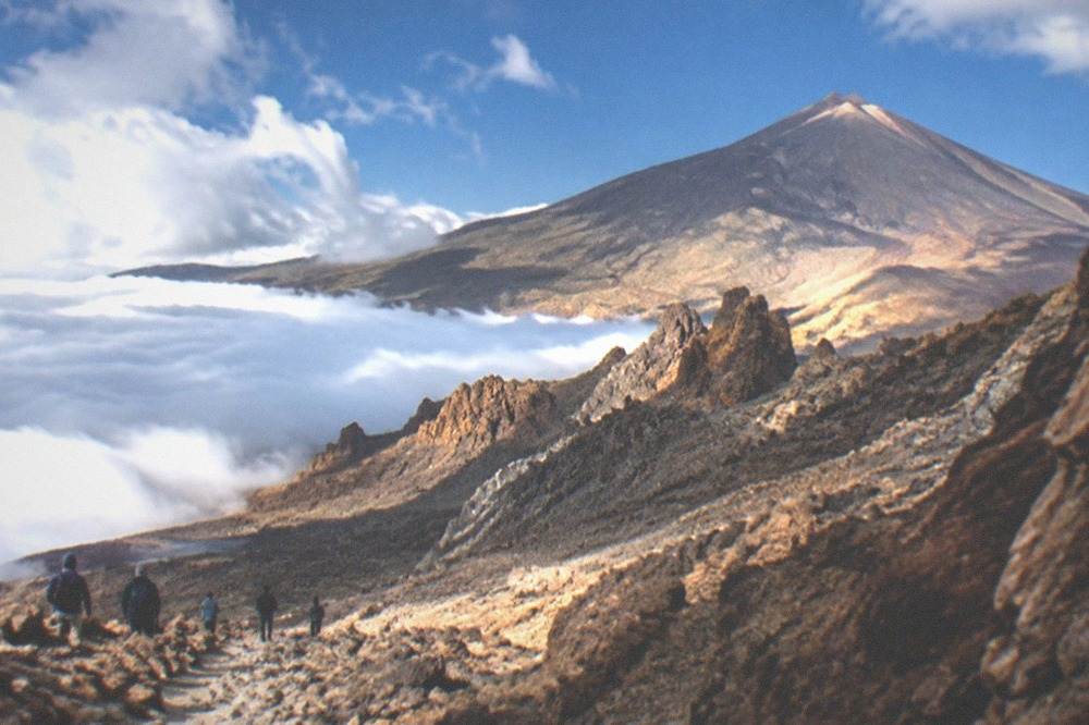 Clouds resting below a sunlit volcanic ridge high on Mount Teide