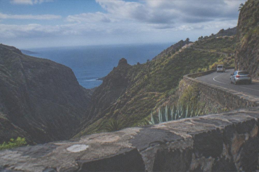 A coastal motorway curve with the sea on one side and hills on the other