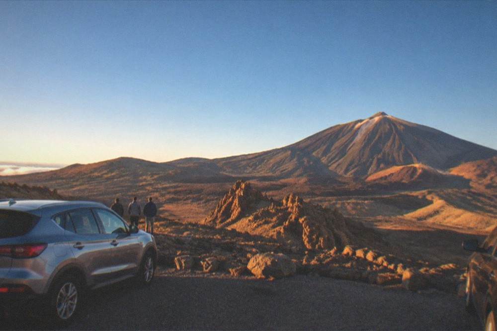Cars parked at a viewpoint overlooking the volcanic plain of Teide National Park