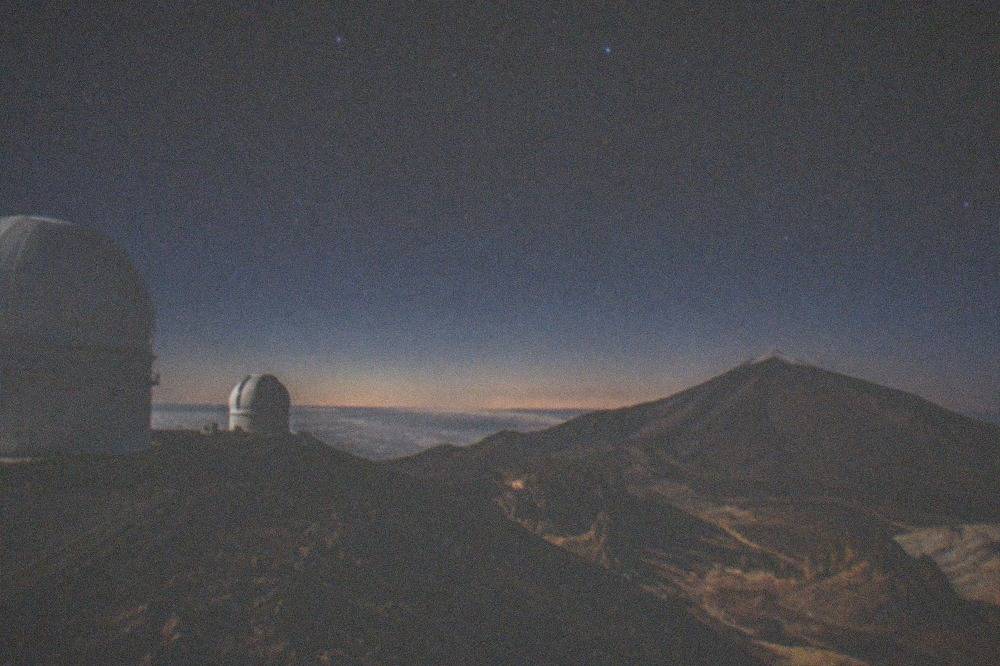 White telescope domes of the Teide Observatory on a high ridge above cloud