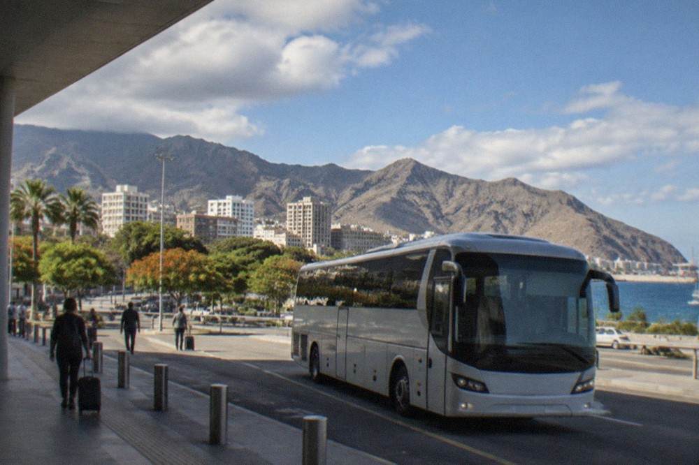 A bus waiting at an airport terminal forecourt under a blue sky