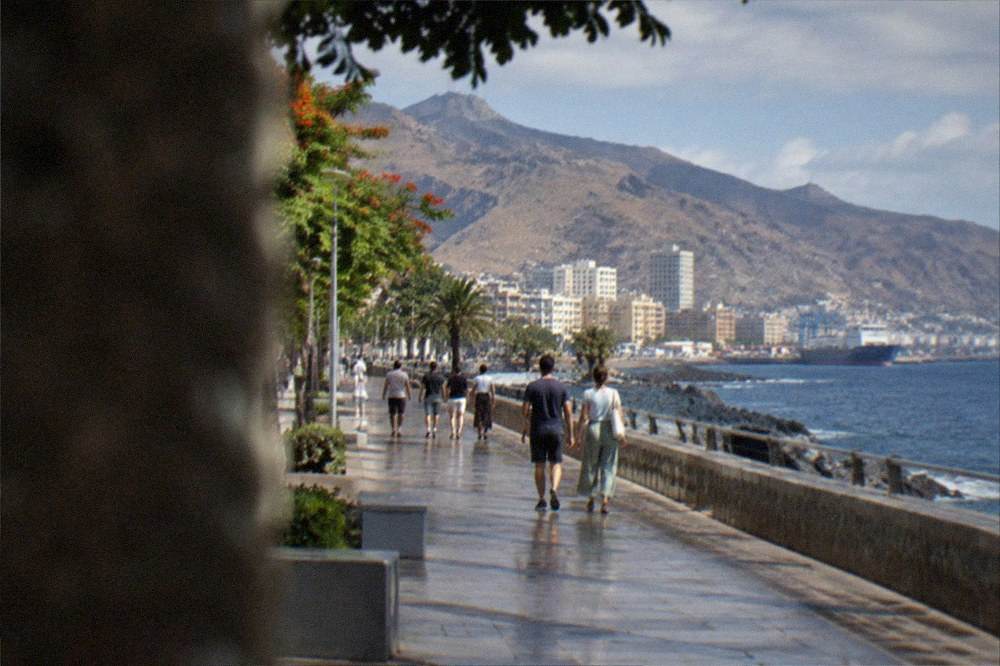 A coastal promenade in a southern Tenerife resort with people walking beside the sea