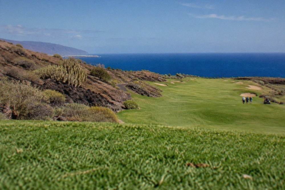 A golf fairway running along the sunny southern coast of Tenerife with the ocean in the distance