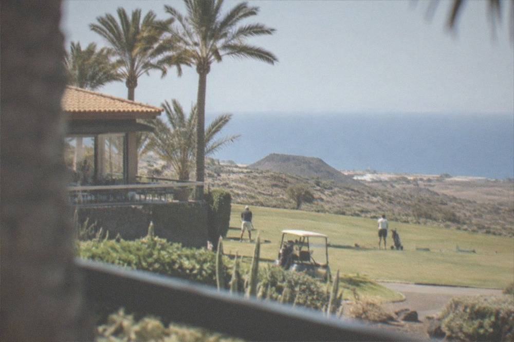 A golf course clubhouse and practice range under palms in a southern Tenerife resort