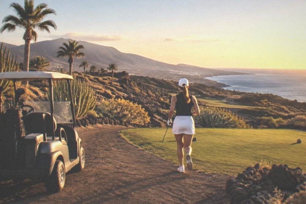 A golf buggy parked beside a tee box with volcanic rock and palms in the background