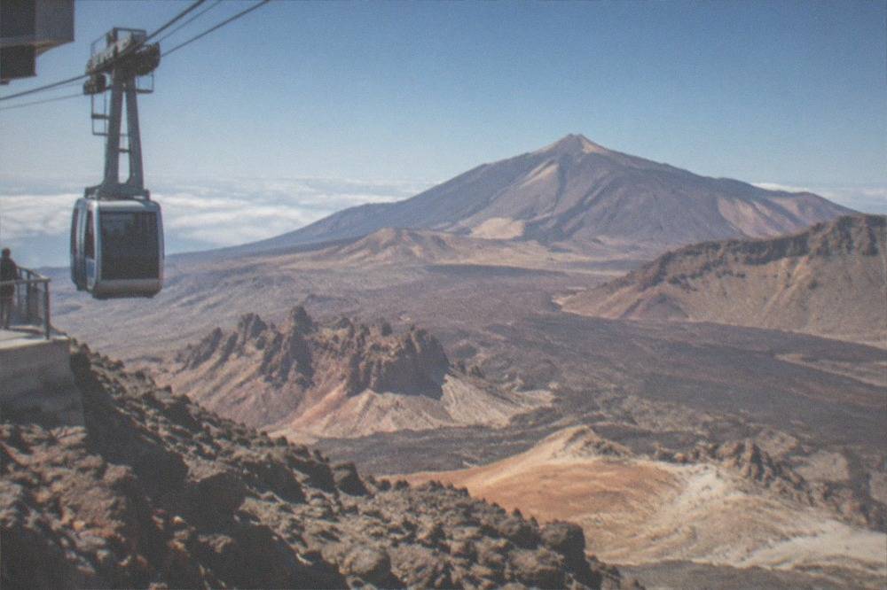 The upper station of the Teide cable car on a rocky slope with the summit crater ridge behind it