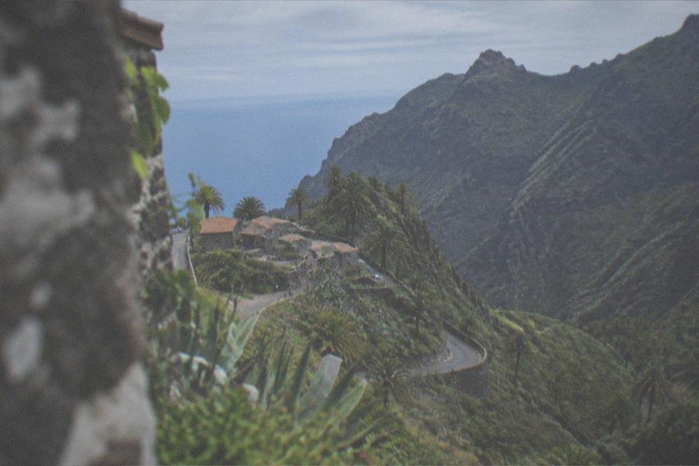 The small stone houses of Masca village on a ridge surrounded by deep green ravines