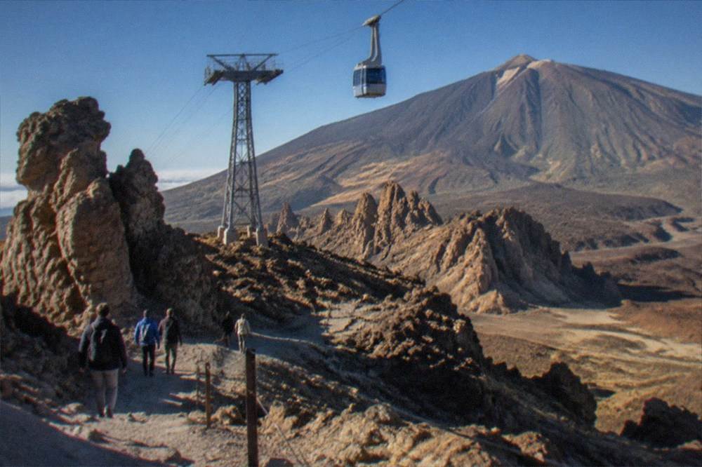 Visitors walking among volcanic rock formations below the Teide cable car line