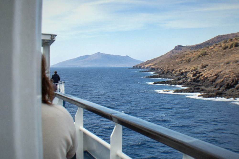 The sea between two Canary Islands seen from a ferry deck with a distant island on the horizon