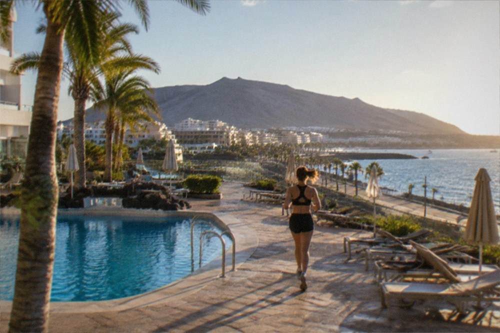 A modern resort hotel pool terrace with palm trees and sun loungers
