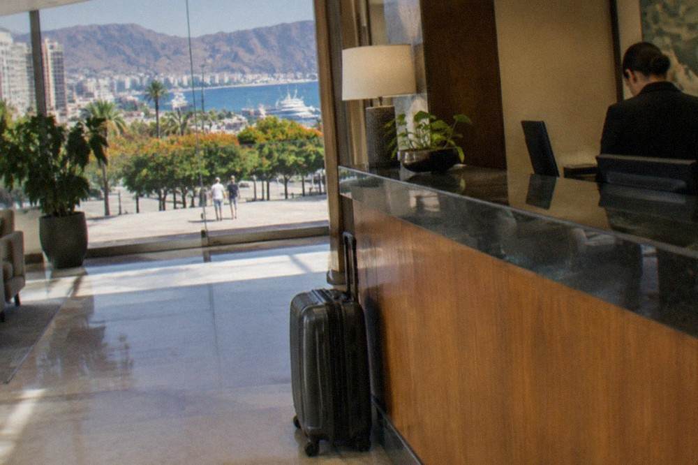 A hotel reception desk with a suitcase parked beside it