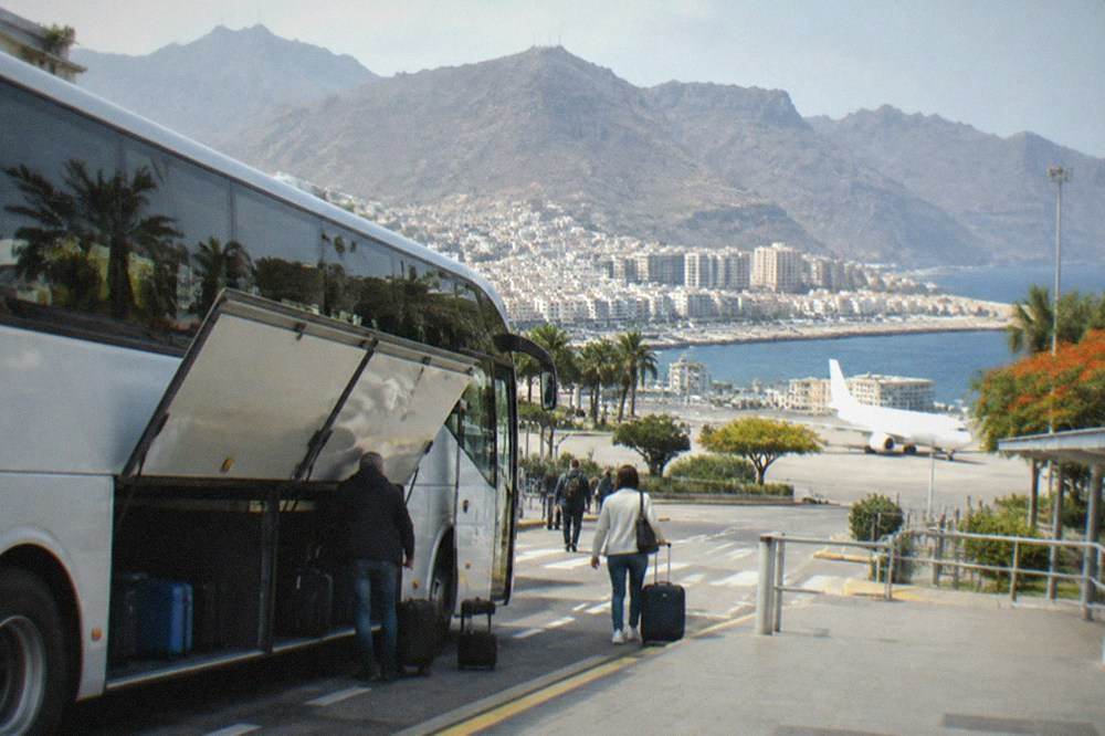 A bus with luggage hold doors open at an island airport kerb