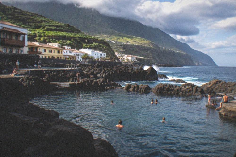 Families swimming in a sheltered pool of sea water among dark rocks