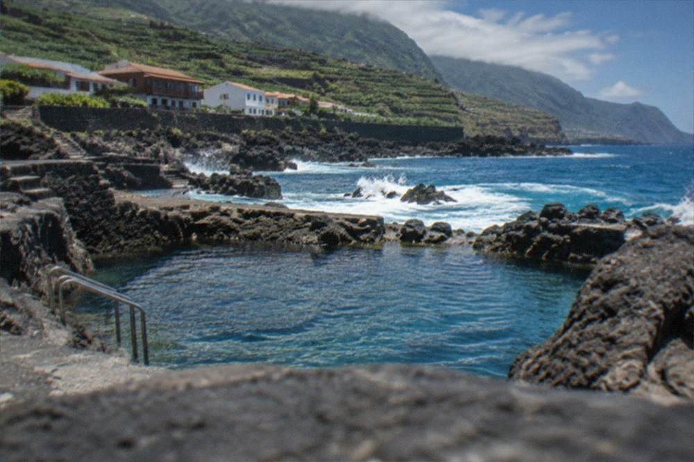 A coastal town with dark rock and blue sea on a bright day