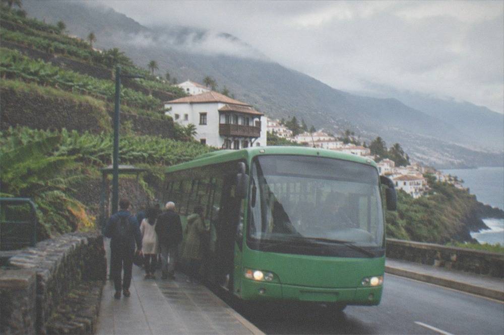 A green Tenerife bus at a stop with passengers boarding