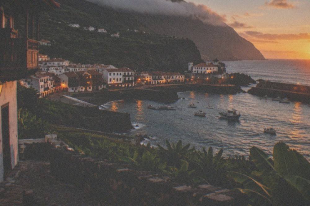 Garachico at dusk with warm lights along the harbour and dark hills behind