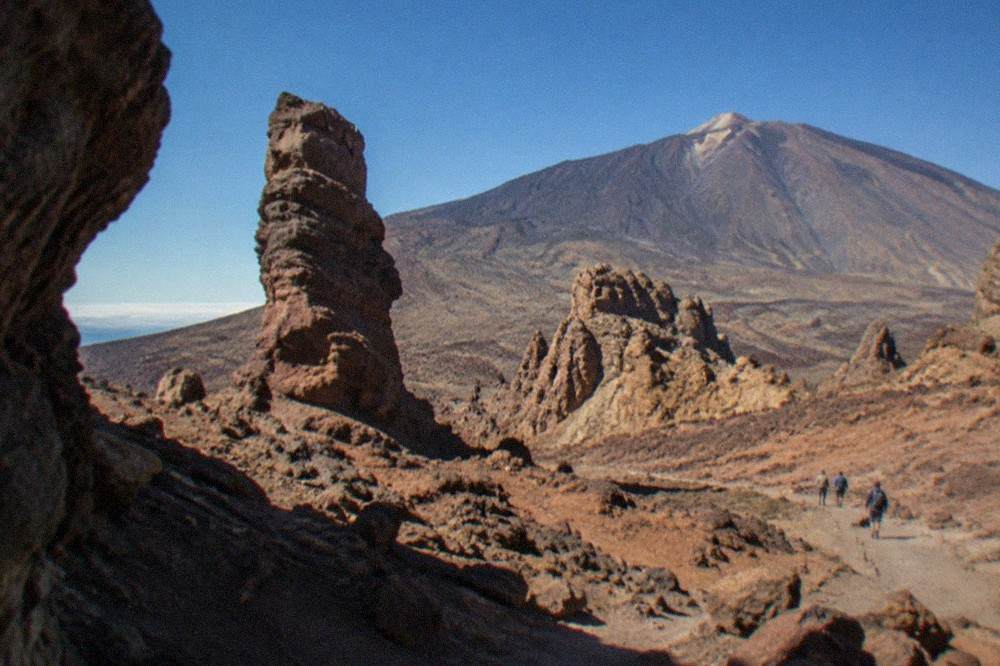 Tall rock formations standing in barren red volcanic ground under a clear sky