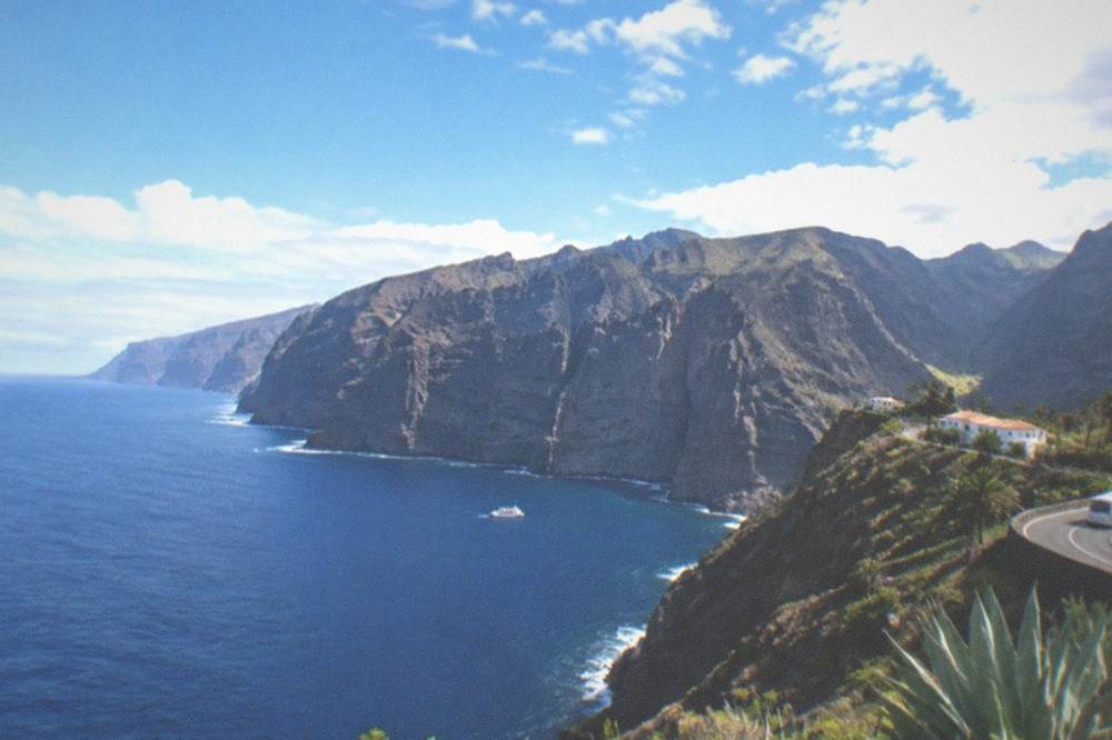 The sea cliffs of Los Gigantes rising straight from blue water with a small boat near their base