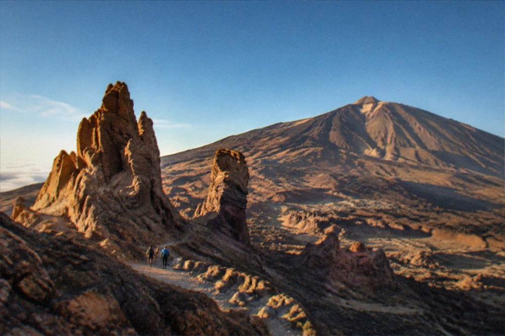 Low golden sunlight across a volcanic landscape with long shadows on reddish rock