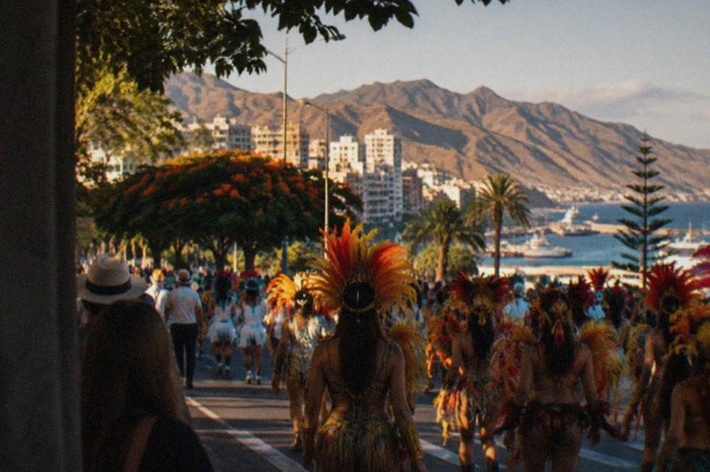 Crowds in costume fill a city street during a carnival parade in Santa Cruz de Tenerife