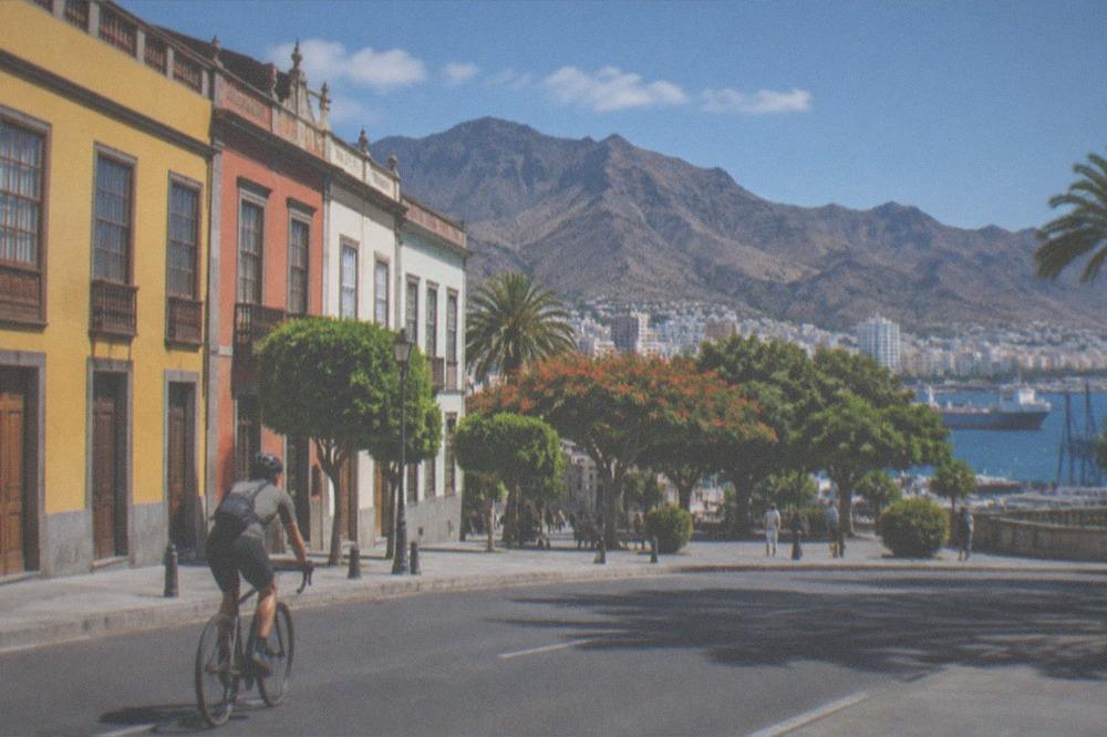 A cyclist riding past colonial-style coloured buildings on a street in Santa Cruz de Tenerife