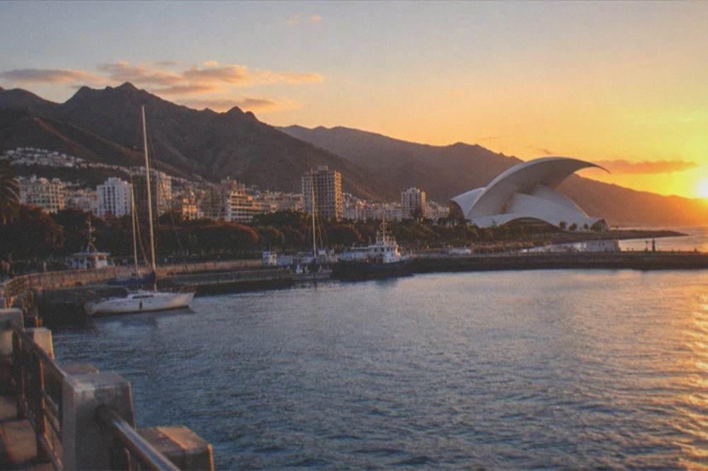 A harbour view of Santa Cruz de Tenerife at dusk with the Auditorio's white roof lit against the sky