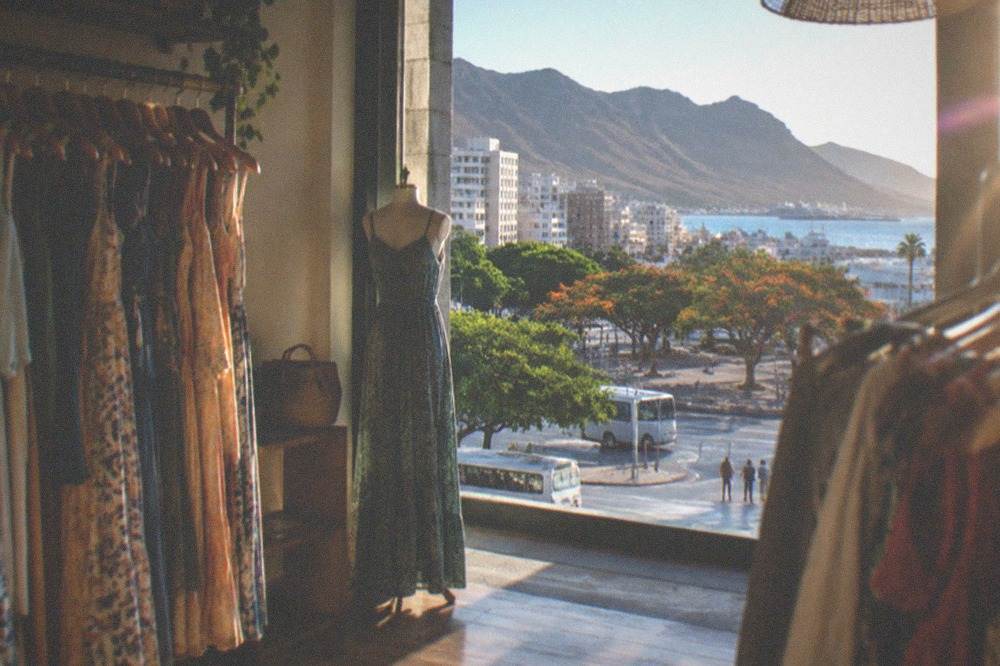A clothing shop interior with rails of summer dresses and a wooden floor
