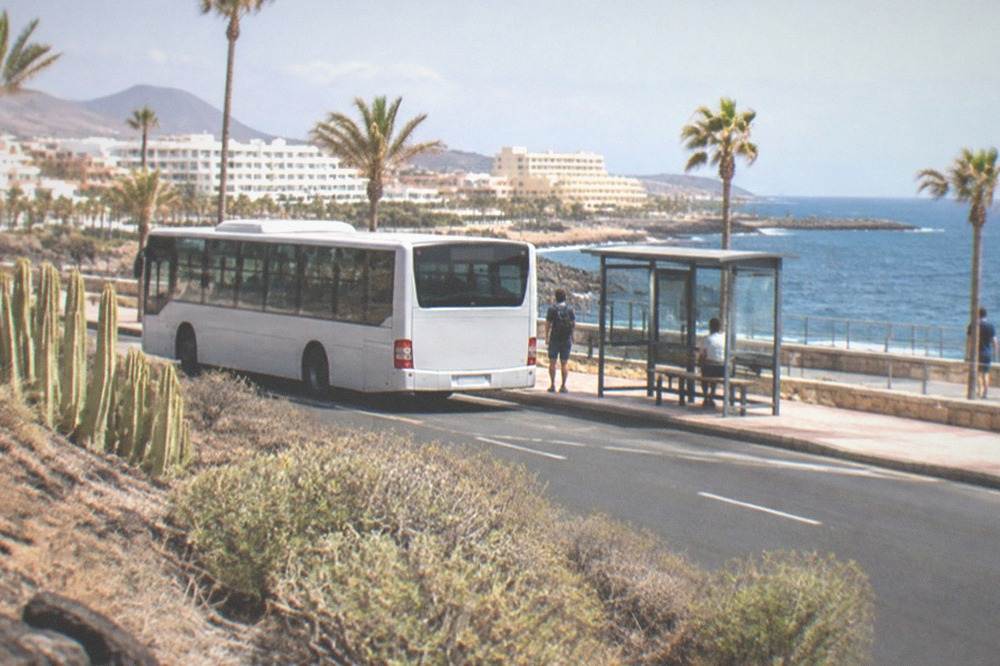 A coastal road at Playa de las Americas with a bus stop and the sea beyond