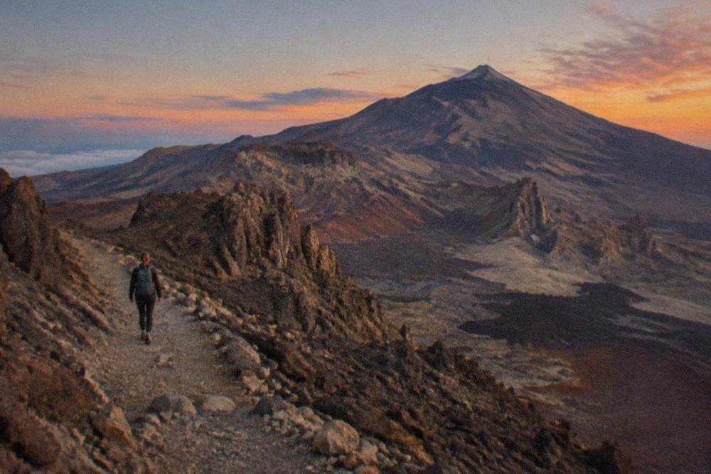 Rocky volcanic slopes in Teide National Park under a pink and orange evening sky