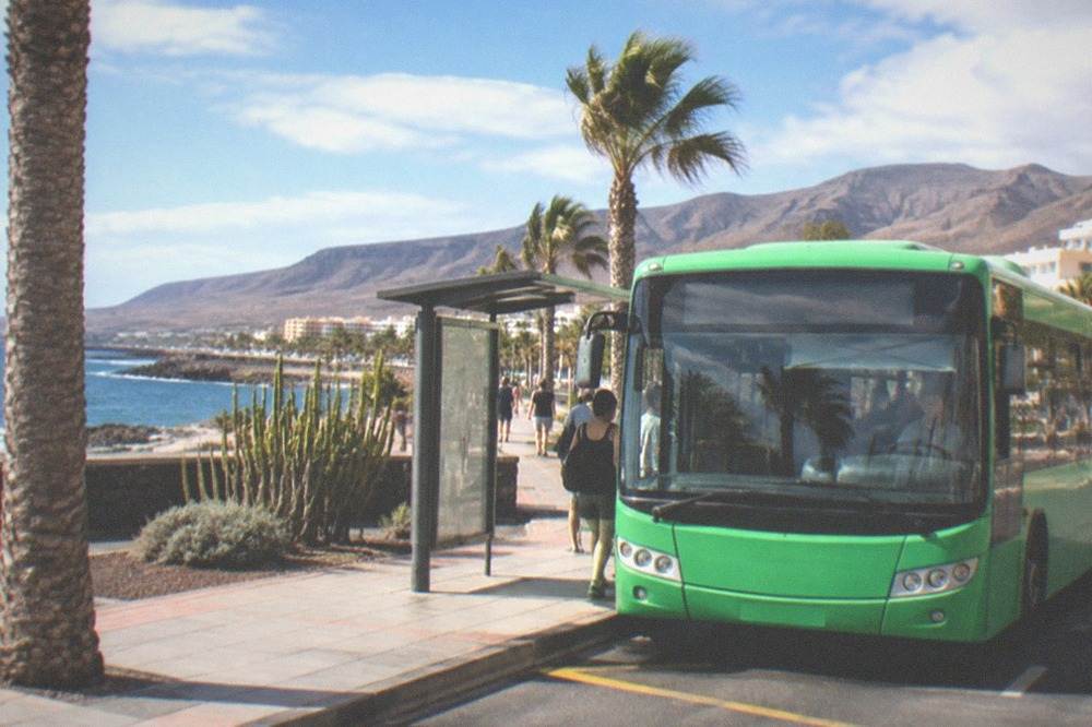 A green island bus at a stop in a Tenerife resort town