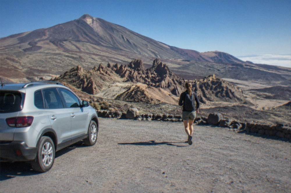 A rental car parked at a viewpoint overlooking volcanic mountains in Teide National Park