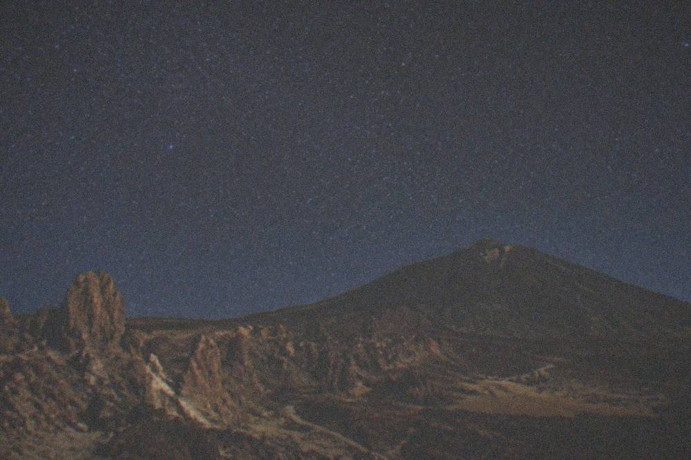 A night sky full of stars above the dark silhouette of Mount Teide