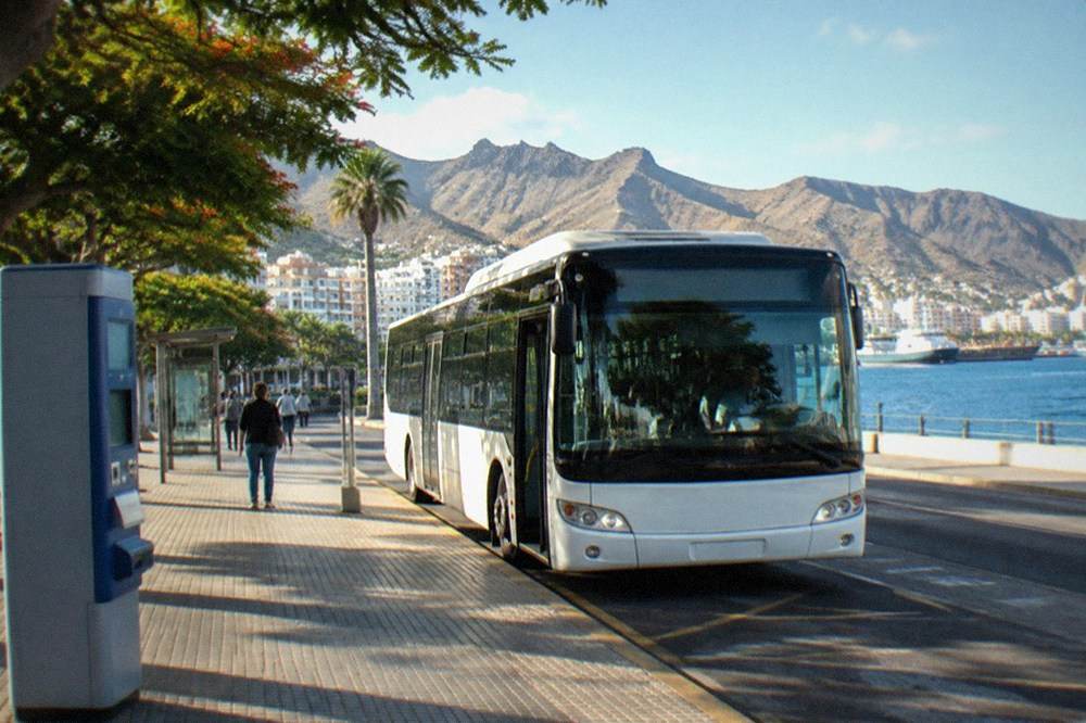 A ticket machine and bus stop sign at a Tenerife airport forecourt