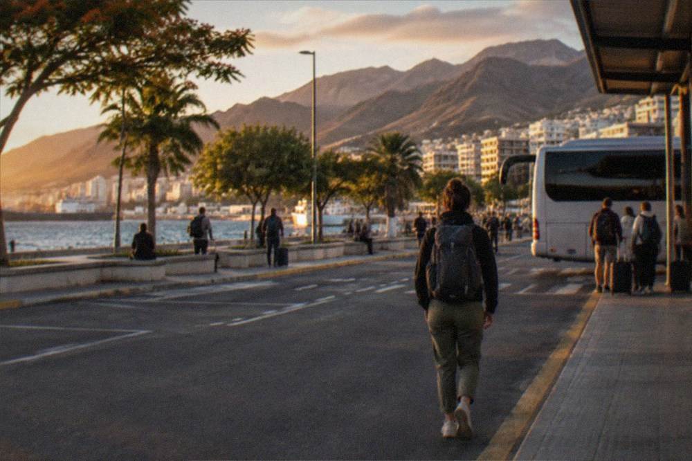 Travellers waiting with rucksacks at an island bus interchange in the evening