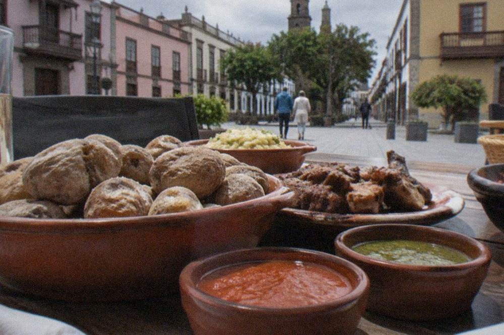 A table of Canarian dishes with small bowls of red and green sauces in a restaurant