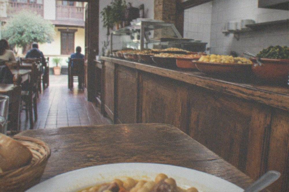 A rustic eating house with wooden tables and a counter of home-cooked dishes
