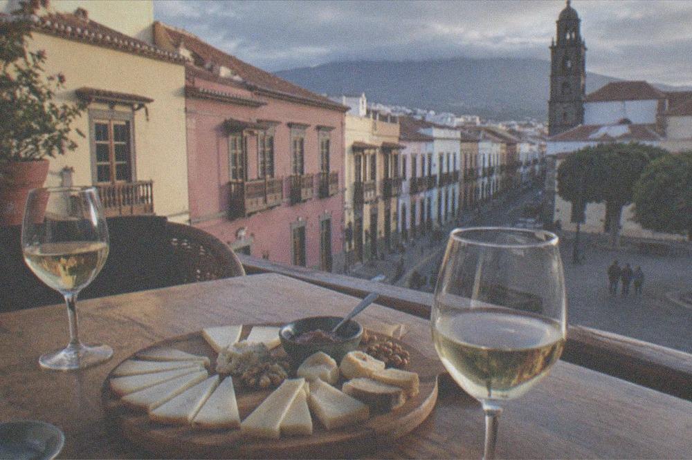 A platter of Canarian cheeses and glasses of wine on a wooden table