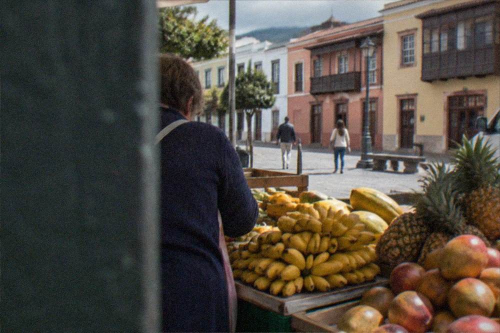 A bunch of small bananas on a market stall with other tropical fruit
