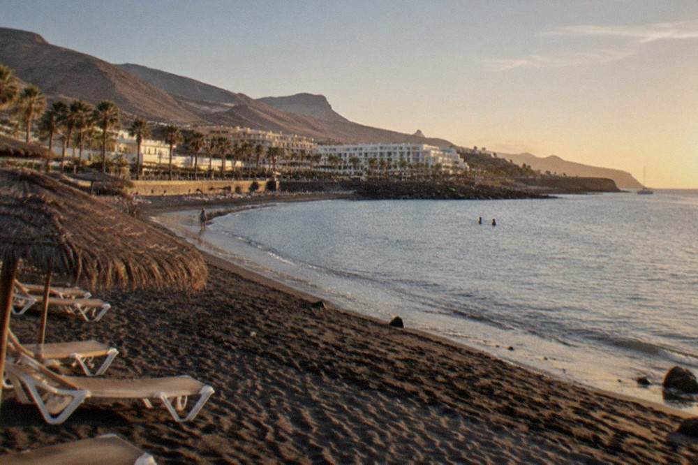 A sunny beach in south Tenerife with calm water and sunbeds