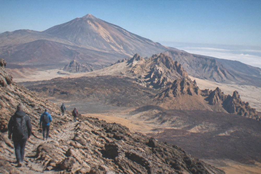 Hikers in warm clothing on a rocky trail high on Mount Teide