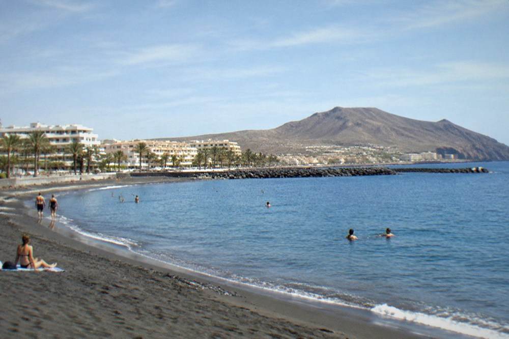 Swimmers in clear water at a sheltered Tenerife beach with breakwaters