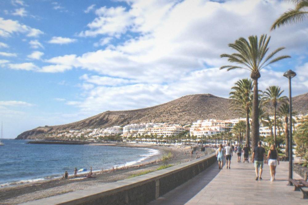 A busy promenade in a southern Tenerife resort town on a summer afternoon