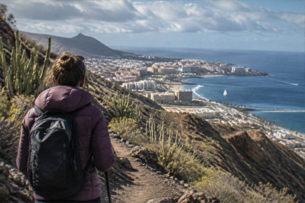 A hiker in a warm jacket on a mountain trail above the clouds in Tenerife